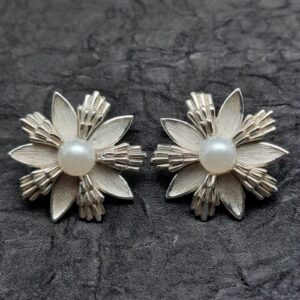 Orecchini a clip firmati Trifari anni ‘60, a forma di fiore stilizzato, in lega Trifanium color argento satinato con dettagli lucidi e perla centrale - VINTAGE AMOREMIO