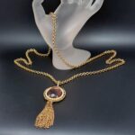 Collana firmata Avon anni ‘60, composta da catena di metallo color oro e ciondolo con grande cristallo ovale ametista e nappa - VINTAGE AMOREMIO